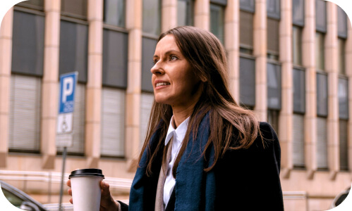 New Zealand manager walks along a pathway to work morning coffee in hand