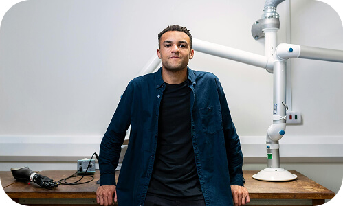 New Zealander standing against a workplace desk