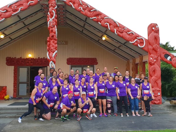 Group photo of the Whānau Whanake family in front of a Marae. Before they set off on a group run..